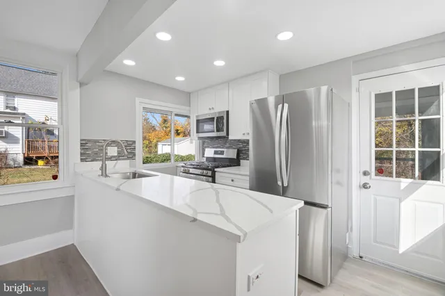 a large kitchen with granite countertop a large counter top stainless steel appliances a sink and cabinets