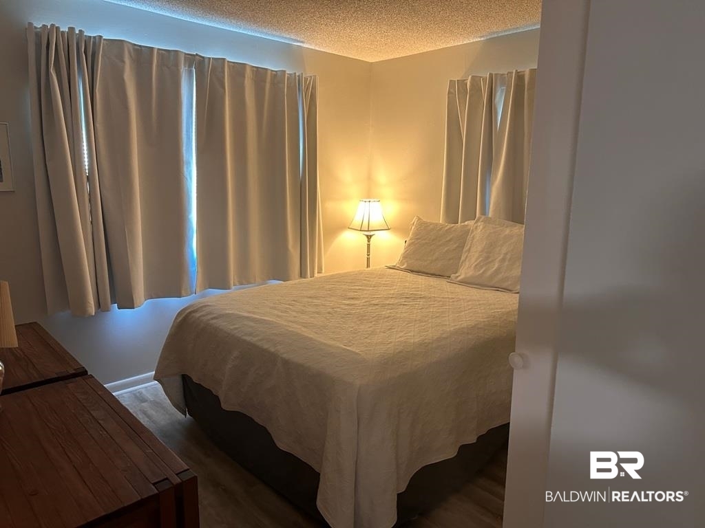 400 Plantation Road, Unit 1113 Gulf Shores, AL 36542 - Photo 9 of 26 Bedroom featuring a textured ceiling and dark hardwood / wood-style floors