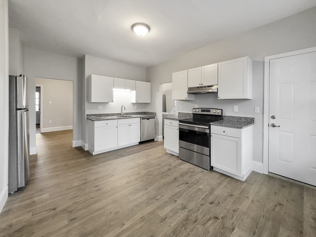a kitchen with granite countertop white cabinets and stainless steel appliances