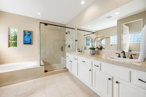 a spacious bathroom with a granite countertop sink a mirror a bathtub and next to a window