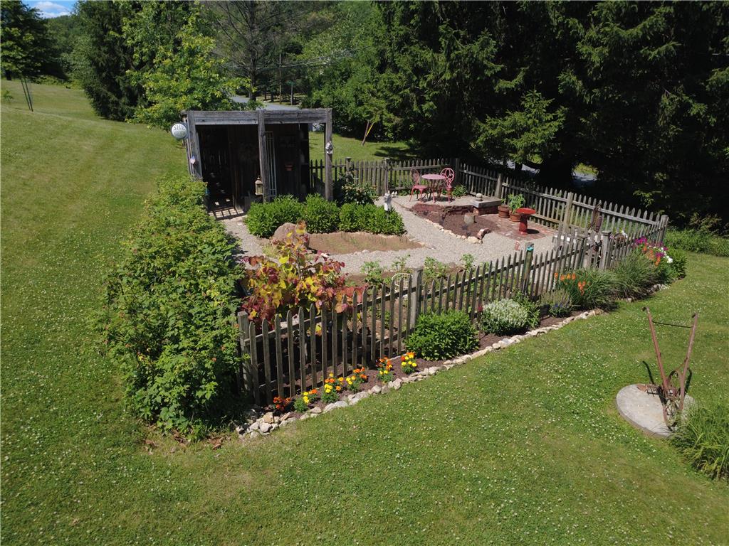 585 Buttermilk Road Hellertown, PA 18055 - Photo 57 of 82 A quaint garden with a wooden privacy fence, gravel paths, and a cozy seating area.