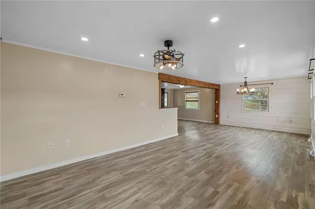 an empty room with wooden floor chandelier and windows