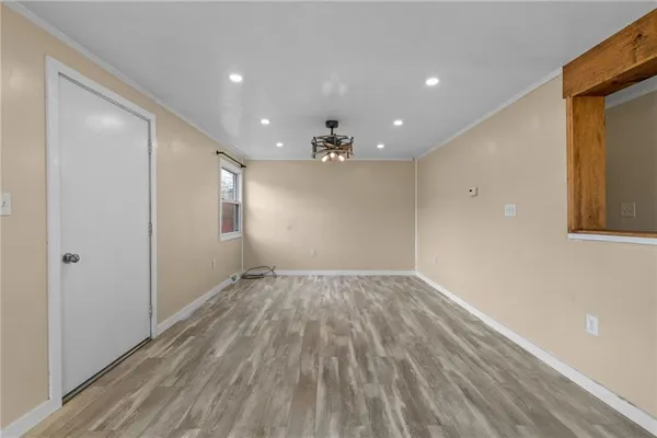 a view of empty room with wooden floor and kitchen view