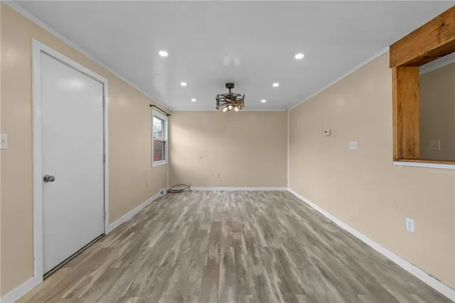 a view of empty room with wooden floor and kitchen view