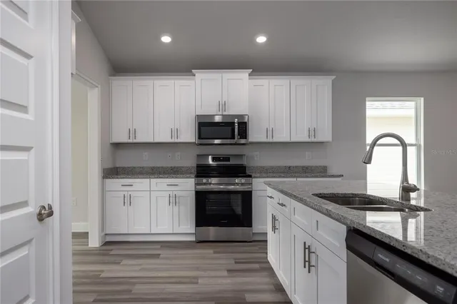 a kitchen with granite countertop white cabinets and stainless steel appliances