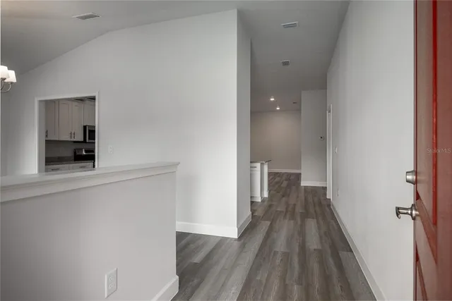 a view of a hallway with wooden floor and a bathroom