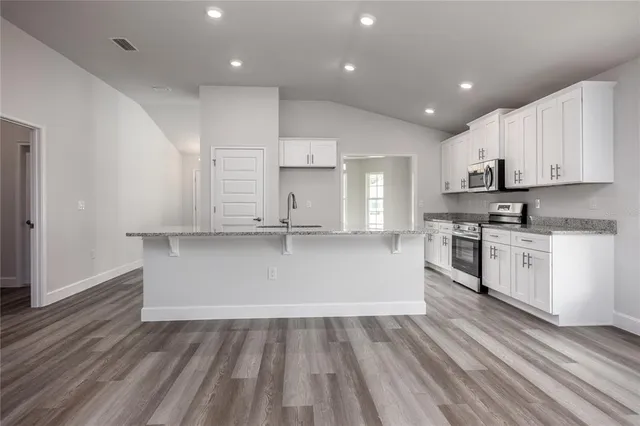 a view of kitchen with granite countertop white cabinets and stainless steel appliances