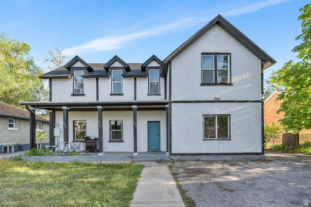 View of front of house with stucco siding, covered porch, and a front yard