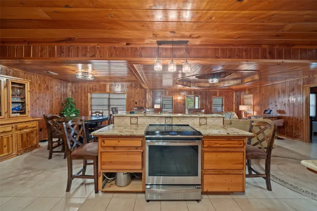 a view of a kitchen with kitchen island a stove a table and chairs