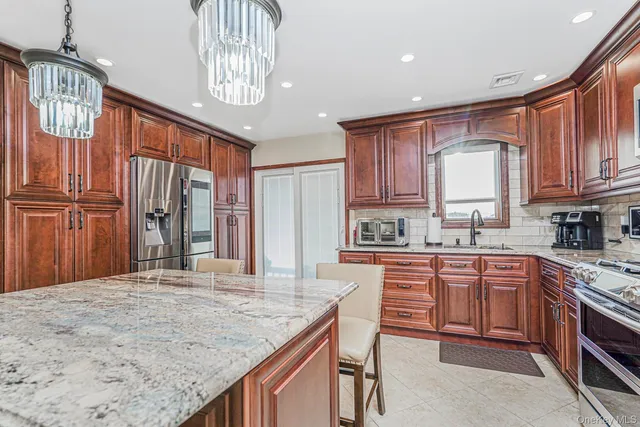 a kitchen with kitchen island granite countertop wooden cabinets a refrigerator a stove a sink and dishwasher with wooden floor