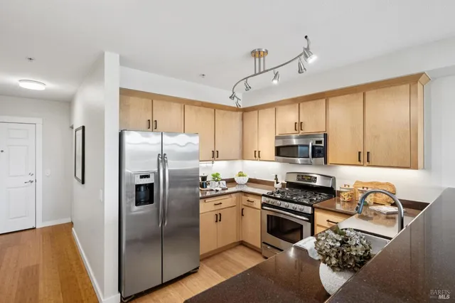 a kitchen with stainless steel appliances a refrigerator a sink a stove a microwave a center island and cabinets