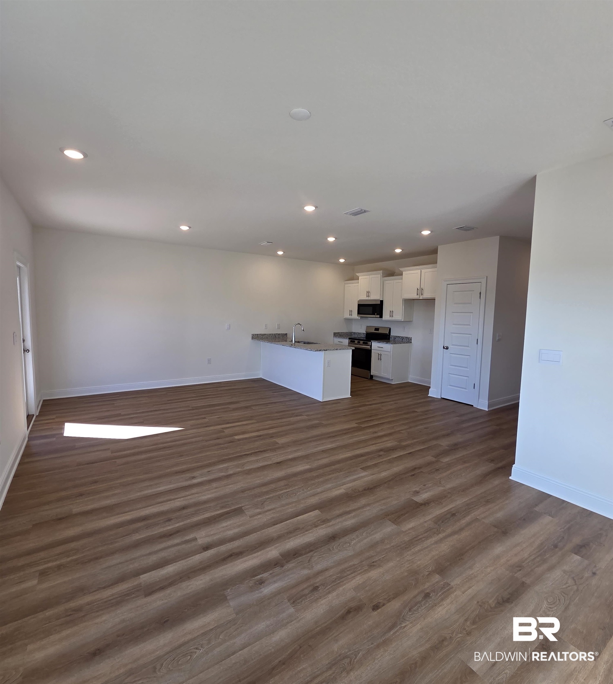 28084 Hallow Trail Elberta, AL 36530 - Photo 21 of 21 Kitchen with open floor plan, white cabinetry, appliances with stainless steel finishes, dark wood finished floors, and a peninsula