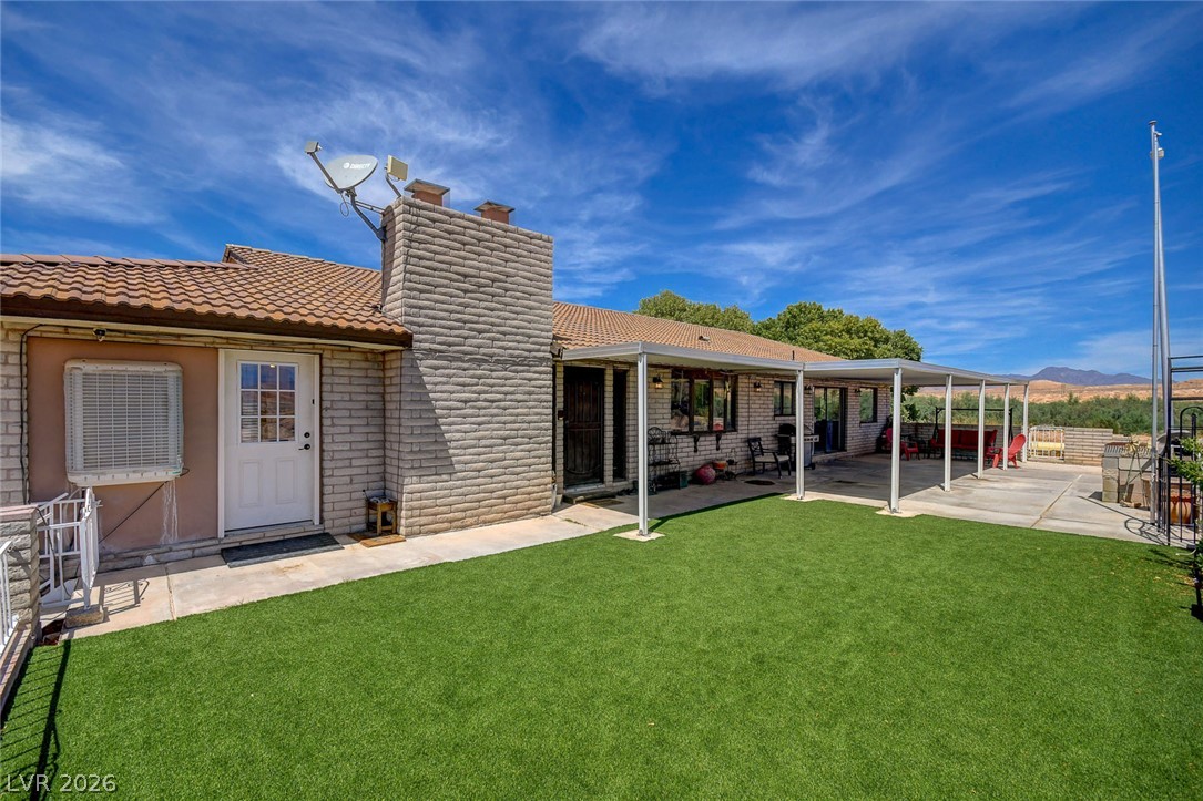1920 Bowman Road Logandale, NV 89021 - Photo 12 of 68 An inviting backyard patio sits beneath a covered overhang beside a neat lawn.