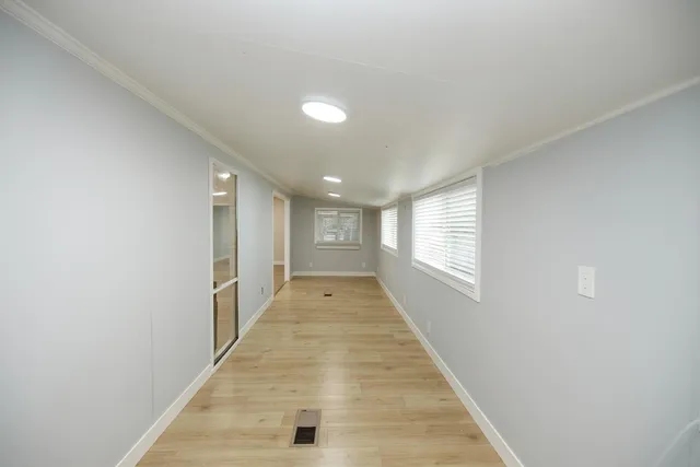 a view of a hallway with wooden floor and window