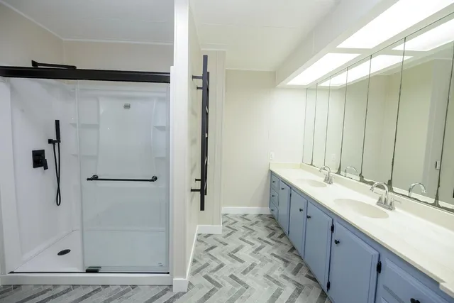 a bathroom with a double vanity sink mirror and shower