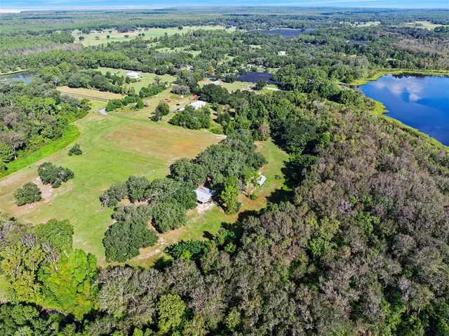 an aerial view of residential houses with outdoor space and trees