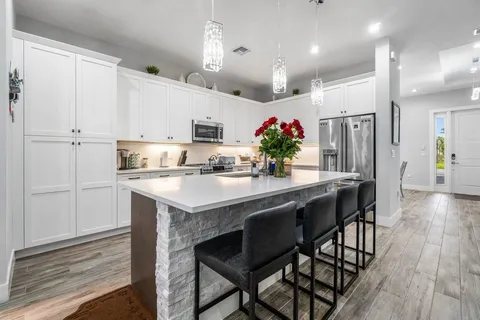 a kitchen with granite countertop kitchen island stainless steel appliances a sink and cabinets