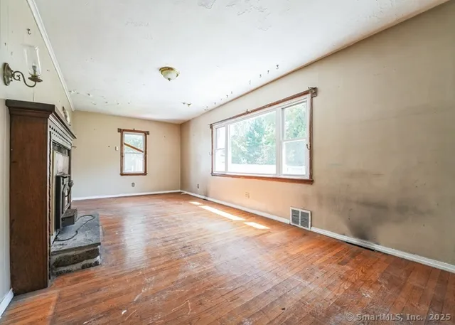 a view of an empty room with a window and wooden floor