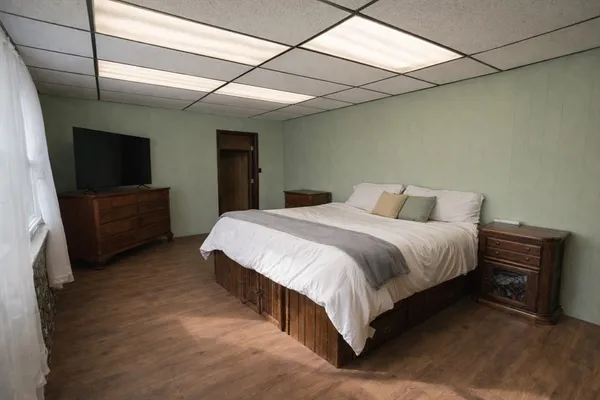 a spacious bedroom with a bed and a flat screen tv