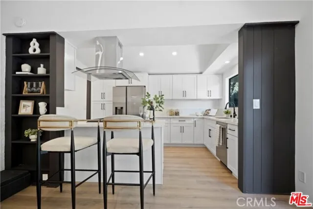 a kitchen with stainless steel appliances a table chairs refrigerator and cabinets