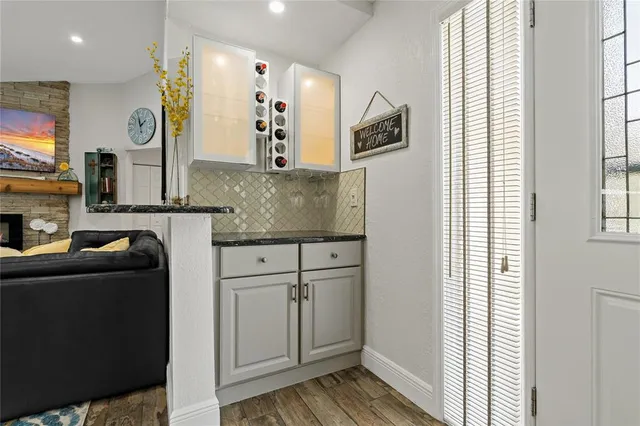a kitchen with stainless steel appliances granite countertop a refrigerator a sink and white cabinets with wooden floor