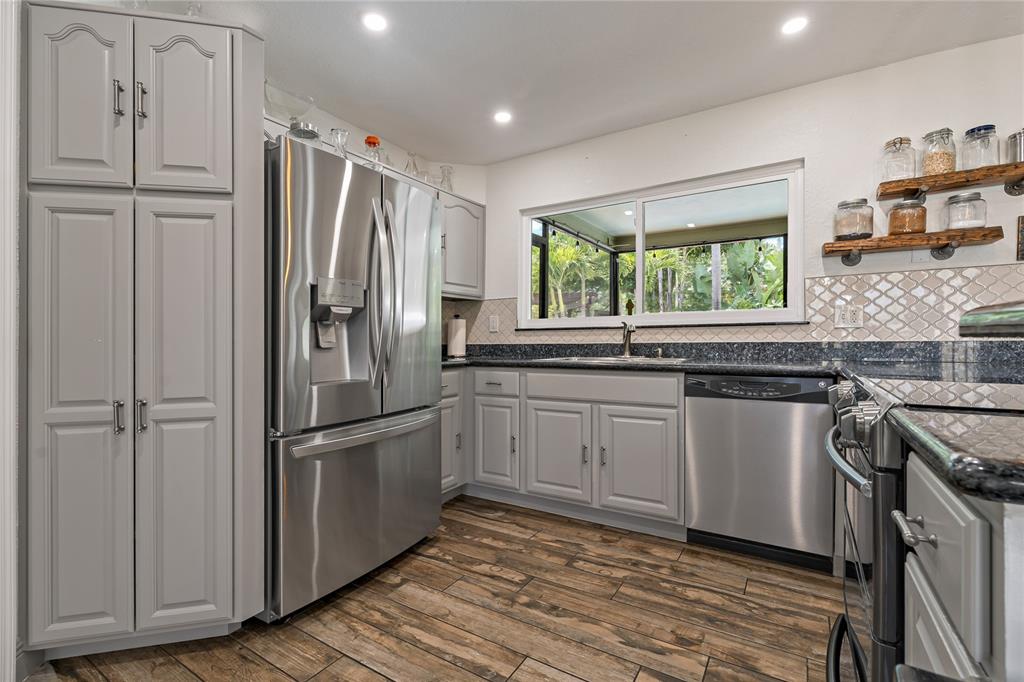 808 Rustic Oaks Drive Palm Harbor, FL 34684 - Photo 15 of 55 a kitchen with stainless steel appliances granite countertop a refrigerator a sink and white cabinets with wooden floor