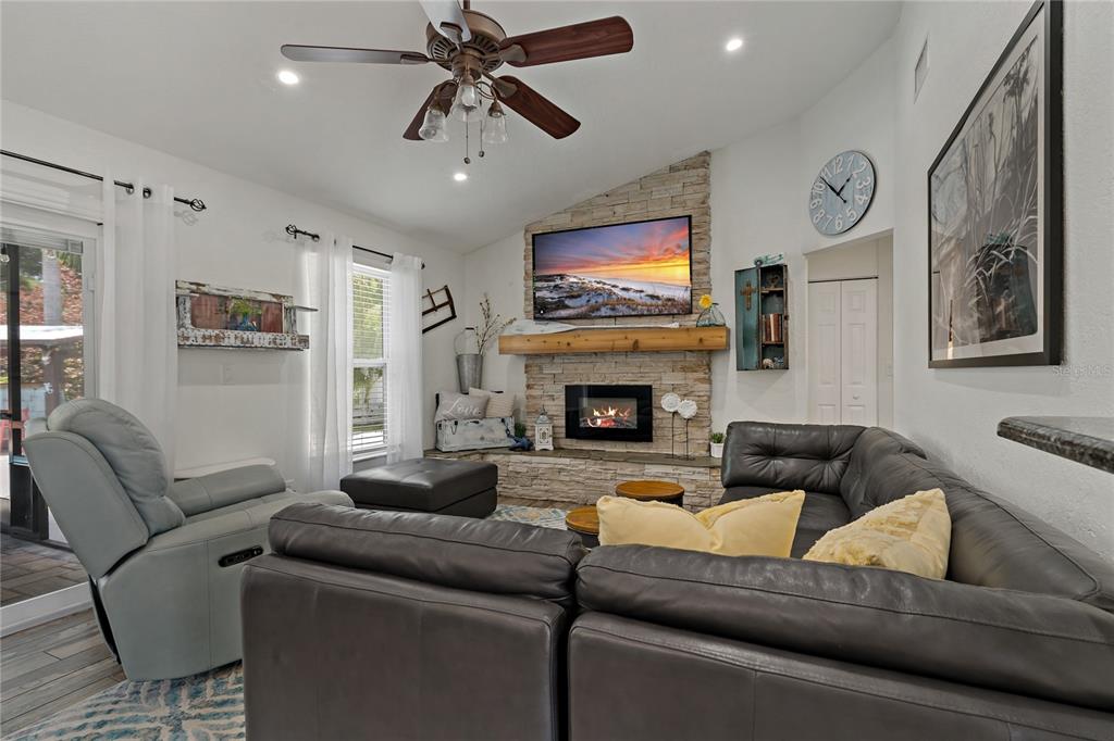 808 Rustic Oaks Drive Palm Harbor, FL 34684 - Photo 17 of 55 a living room with furniture a flat screen tv and a fireplace
