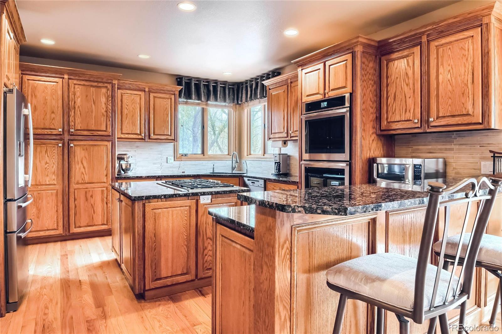 3935 Pierson Street Wheat Ridge, CO 80033 - Photo 8 of 40 a kitchen with stainless steel appliances granite countertop a stove a sink and a refrigerator