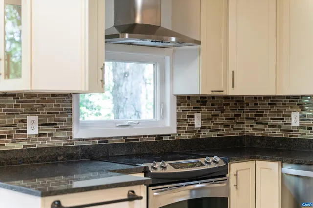 a kitchen with granite countertop a sink a stove and cabinets