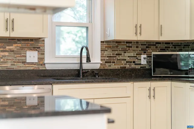 a kitchen with granite countertop white cabinets and a sink