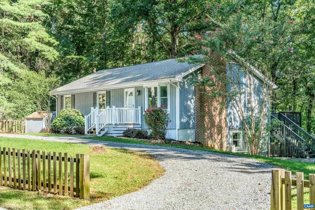 a view of a house with a small yard plants and large trees