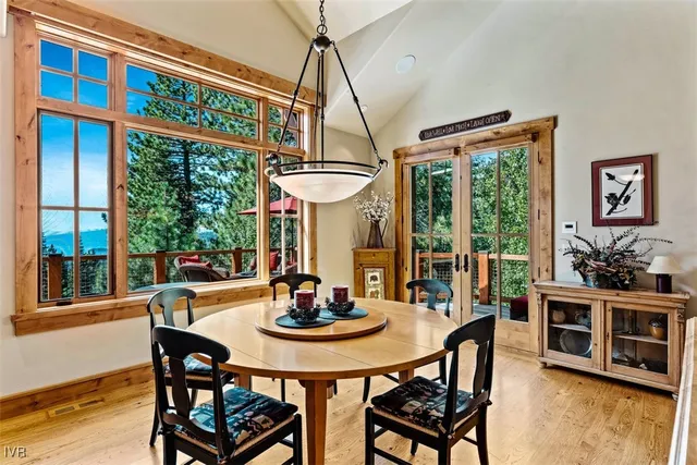 a dining room with furniture a floor to ceiling window and wooden floor