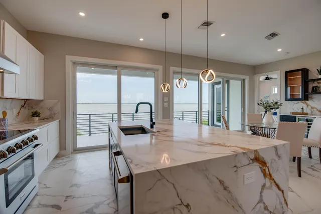 a kitchen with kitchen island a dining table chairs sink and a stove