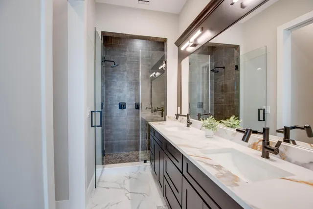 a bathroom with a granite countertop sink a mirror and a shower