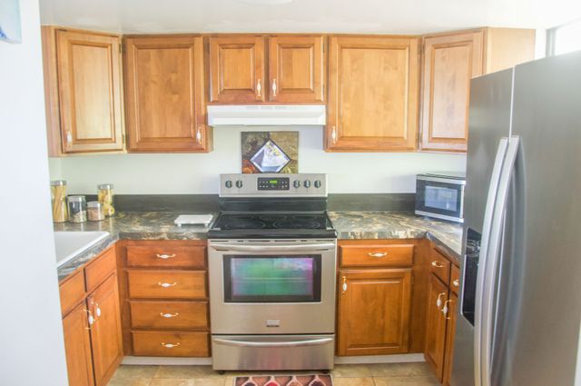 a kitchen with stainless steel appliances granite countertop a refrigerator and a stove top oven
