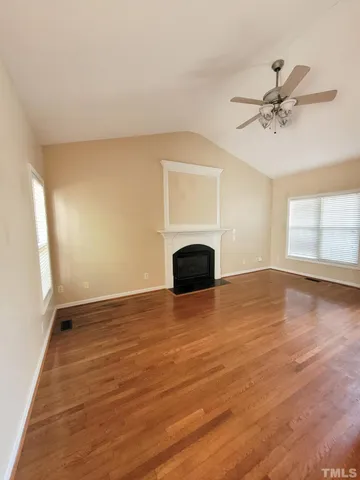 a view of empty room with wooden floor and fan
