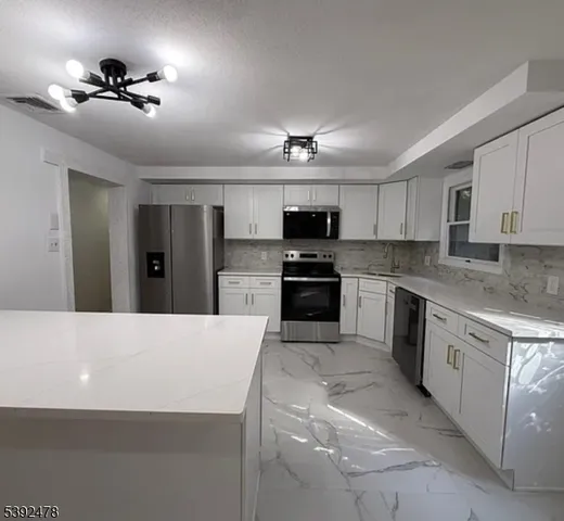 a kitchen with kitchen island a sink stainless steel appliances and cabinets