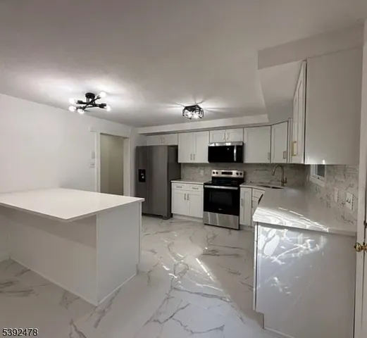 a kitchen with granite countertop a refrigerator and a stove top oven