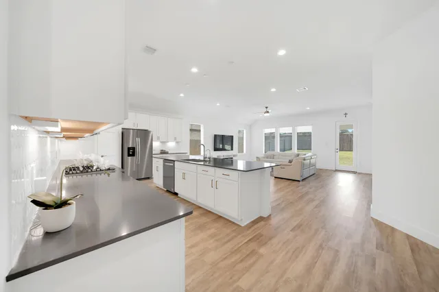 a open kitchen with white cabinets and wooden floor