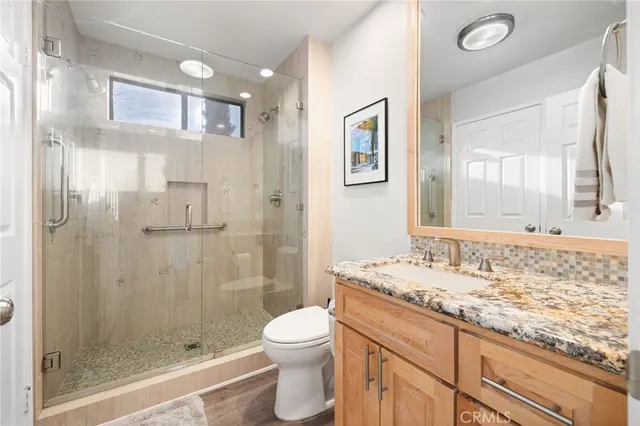 a bathroom with a granite countertop sink a toilet and shower