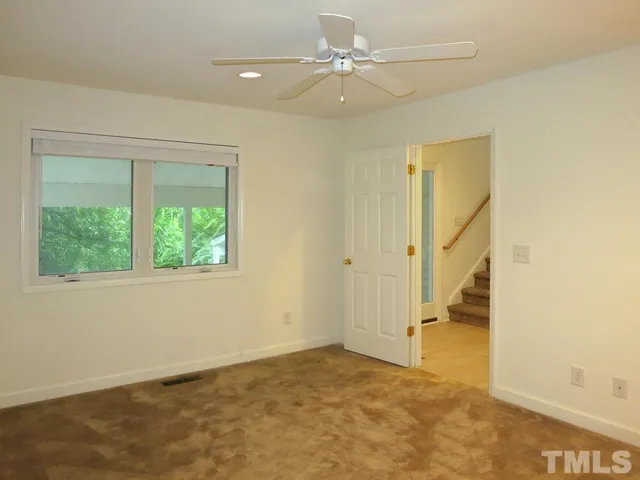 an empty room with a ceiling fan and a window