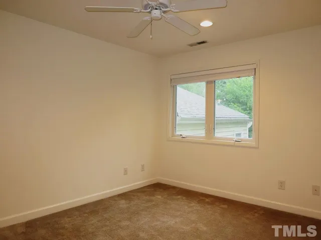 an empty room with a window and a fan