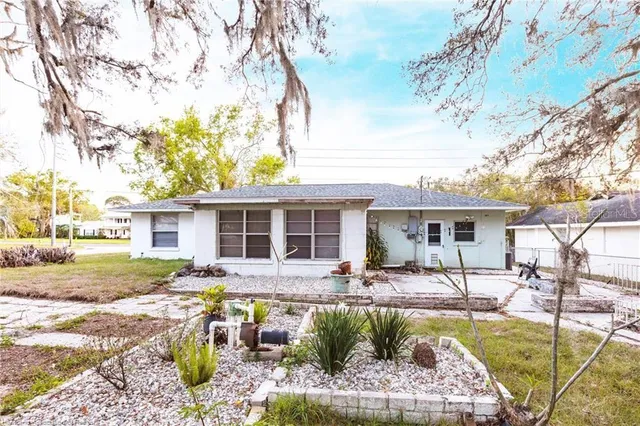 a front view of a house with a garden and trees