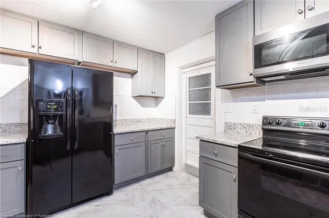 a kitchen with stainless steel appliances granite countertop a refrigerator and a stove top oven
