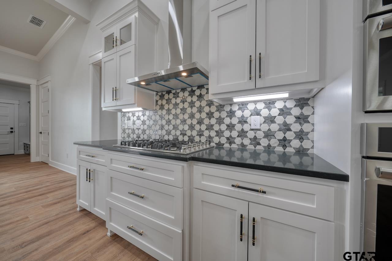 19383 Ridge Point Circle Lindale, TX 75771 - Photo 16 of 48 a kitchen with white cabinets and a wooden floor