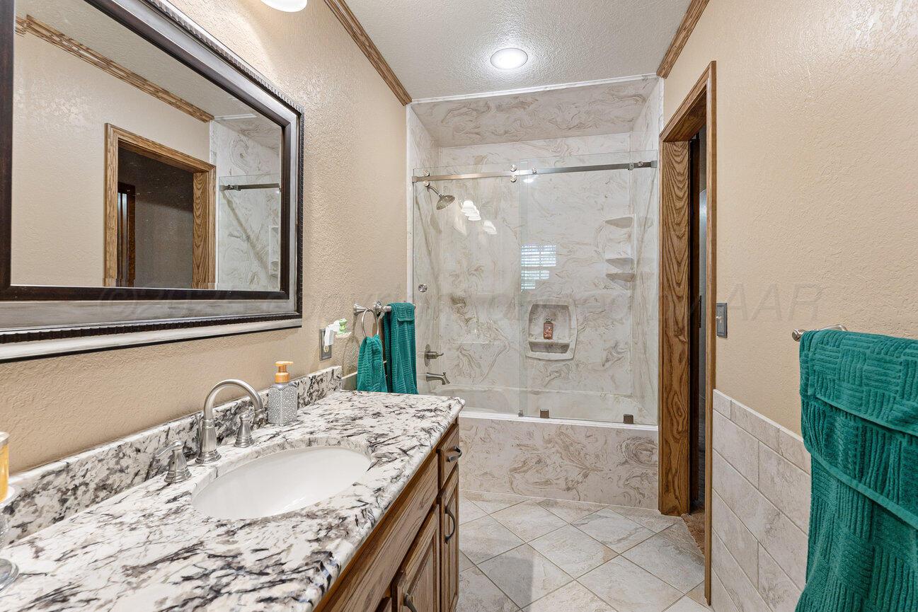 148 Buffalo Trail Fritch, TX 79036 - Photo 36 of 81 a bathroom with a granite countertop sink a mirror and a shower