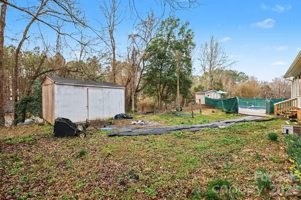 a view of a swimming pool with a bench and trees in the background