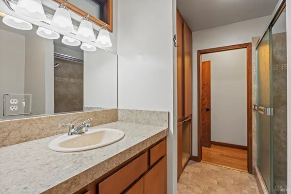 a bathroom with a granite countertop sink a mirror and a shower