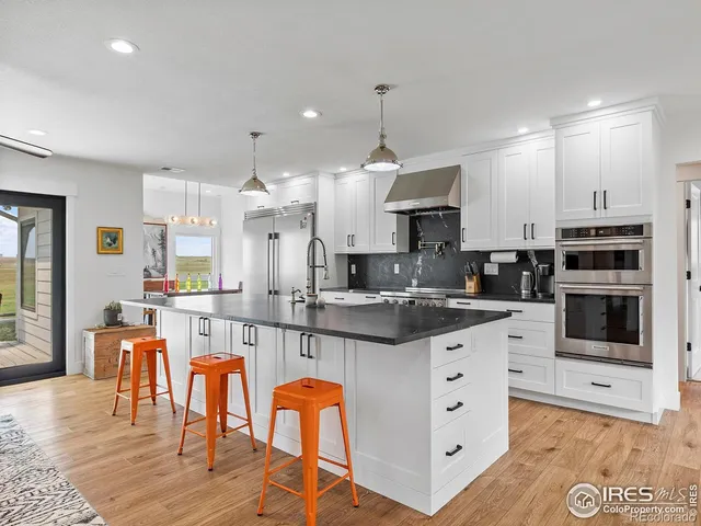 a large kitchen with stainless steel appliances kitchen island granite countertop a large stove a sink a dining table and chairs