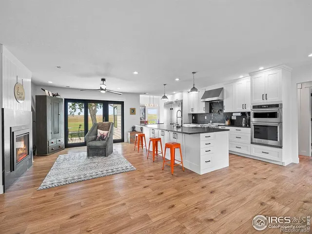 a large kitchen with stainless steel appliances granite countertop a stove a sink a refrigerator and white cabinets with wooden floor